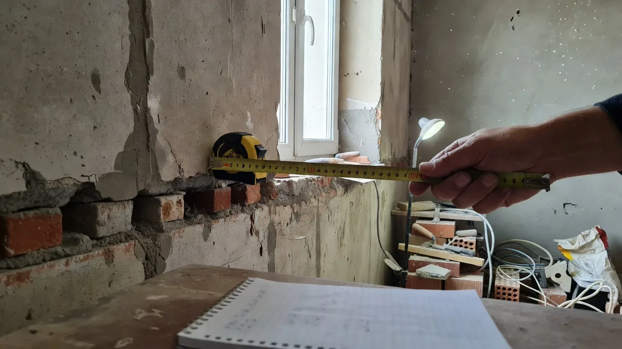 Замер площади стены рулеткой для расчёта сметы на покраску квартиры в Тюмени